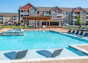 Thumbnail 19 of 28 - A pool with sun loungers and a building in the background. at Grays Creek Apartments, Cordova