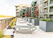 Thumbnail 15 of 37 - A patio with a table and chairs is surrounded by a metal fence and apartment buildings at Harbor Side at Conwood Flats Apartments in Uptown Memphis, TN