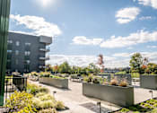 Thumbnail 16 of 37 - A sunny day at a modern outdoor seating area with benches and planters at Harbor Side at Conwood Flats Apartments in Uptown Memphis, TN
