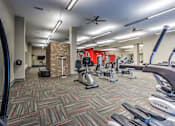 Thumbnail 12 of 14 - A gym with a variety of exercise equipment including treadmills, elliptical machines, and weights at Highland Row Apartments, TN, 38111