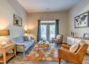 Thumbnail 2 of 14 - A living room with a grey couch, a brown chair, and a wooden coffee table at Highland Row Apartments, Memphis, 38111