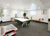 Thumbnail 29 of 38 - A conference room with a white table, chairs, and a foosball table.