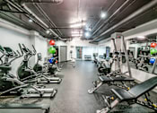 Thumbnail 30 of 38 - A gym with a row of treadmills and elliptical machines.