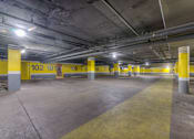 Thumbnail 26 of 38 - A parking garage with yellow poles and concrete floors.at Iris Luxury Apartments, Memphis  