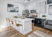 Thumbnail 5 of 38 - A modern kitchen with a white island and black appliances.at Iris Luxury Apartments, Memphis, 38105  