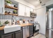 Thumbnail 14 of 28 - a kitchen with modern gray and white cabinets at Kiwi Goji Apartments, Memphis, Tennessee