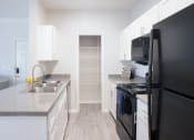 Thumbnail 2 of 24 - a kitchen with white cabinets and black appliances at Lincoln at Wolfchase, Tennessee