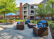 Thumbnail 16 of 24 - our apartments showcase a large deck with lounge chairs and a fire pit at Lincoln at Wolfchase, Cordova Tennessee
