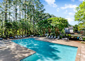 Thumbnail 16 of 29 - A large swimming pool surrounded by trees and lounge chairs. at Manchester at Mansell, Roswell 