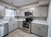 Thumbnail 14 of 29 - A modern kitchen with a stainless steel dishwasher, oven, and microwave. at Manchester at Mansell, Roswell, 30076 