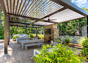 Thumbnail 22 of 29 - A patio with a fireplace and a bench under a roof. at Manchester at Mansell, Roswell, 30076 