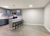 Thumbnail 3 of 29 - A kitchen with a bar area and grey cabinets. at Manchester at Mansell, Roswell Georgia 