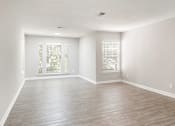 Thumbnail 8 of 29 - A room with wooden flooring and two windows with blinds. at Manchester at Mansell, Roswell, GA