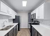 Thumbnail 13 of 29 - A kitchen with black appliances and white cabinets. at Manchester at Mansell, Roswell, GA