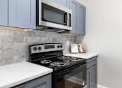 Thumbnail 11 of 29 - A kitchen with a black stove at Manchester at Mansell, Roswell, GA 30076 