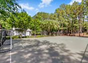 Thumbnail 25 of 29 - A tennis court surrounded by trees and a building in the background. at Manchester at Mansell, Roswell Georgia 