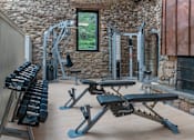Thumbnail 23 of 27 - A home gym with a variety of equipment including a bench, dumbbells, and a cable machine. at Mill House at East Cobb, Georgia 