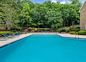 Thumbnail 13 of 27 - A large swimming pool surrounded by trees and a stone building. at Mill House at East Cobb, Marietta Georgia 