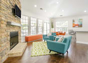 Thumbnail 30 of 30 - A living room with a stone fireplace and a flat screen TV mounted above it.
