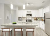 Thumbnail 1 of 30 - A kitchen with a granite countertop and white cabinets.