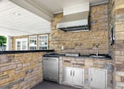 Thumbnail 25 of 30 - A kitchen with a stone wall and a stainless steel dishwasher.