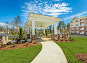 Thumbnail 27 of 30 - A white covered walkway leads to a building with a stone pillar on each side.