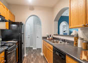 Thumbnail 7 of 30 - A kitchen with wooden cabinets and a black refrigerator.
