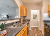 Thumbnail 6 of 30 - A kitchen with wooden cabinets and a stainless steel sink.