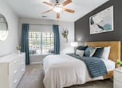 Thumbnail 13 of 30 - A bedroom with a large bed, a ceiling fan, and a window with curtains.