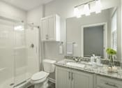 Thumbnail 17 of 30 - A white bathroom with a toilet, sink, and mirror.
