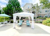 Thumbnail 24 of 30 - A white canopy is set up over a table and chairs.