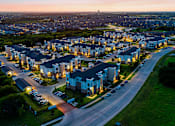Thumbnail 25 of 25 - A residential area with houses and parked cars is shown at dusk.