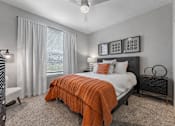 Thumbnail 6 of 25 - A bedroom with a bed covered in an orange blanket.
