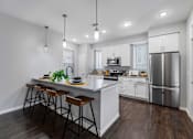 Thumbnail 2 of 25 - A modern kitchen with a bar area and stools.