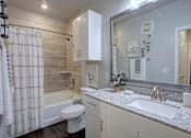 Thumbnail 7 of 25 - A bathroom with a white toilet, sink, and shower curtain.
