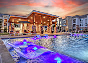 Thumbnail 20 of 25 - A pool with a waterfall and lights in the middle of it.