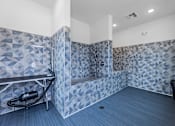Thumbnail 16 of 25 - A bathroom with a blue tiled shower and a black trash can.