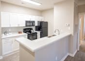 Thumbnail 2 of 31 - White Cabinetry and Black Appliances Kitchen with Breakfast Barat Polos at Hudson Corners Apartments, South Carolina 29650