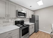 Thumbnail 13 of 25 - A kitchen with a stove, oven, refrigerator, and microwave. at Station Heights, Alpharetta Georgia 