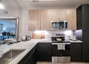 Thumbnail 3 of 28 - a kitchen with black appliances and granite counter tops at Station at Old Town, Lewisville, TX
