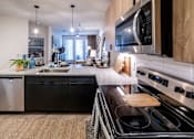 Thumbnail 4 of 28 - open floorplan kitchen with island and updated appliances at Station at Old Town, Lewisville, 75057