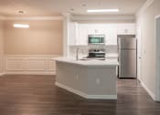 Thumbnail 7 of 51 - A kitchen with white cabinets and a wooden floor.