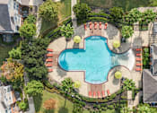 Thumbnail 2 of 16 - An aerial view of a swimming pool surrounded by a red fence and palm trees at The Fenwick Apartments, Humble, TX, 77396