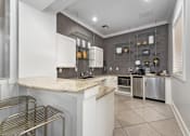 Thumbnail 9 of 16 - A kitchen with white cabinets and a marble countertop at The Fenwick Apartments, Humble, TX, 77396