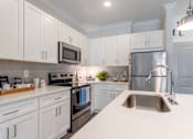 Thumbnail 1 of 15 - A kitchen with white cabinets and a stainless steel refrigerator.at The One at Millington, Millington, TN