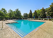 Thumbnail 17 of 33 - A large outdoor swimming pool surrounded by trees.