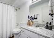 Thumbnail 11 of 23 - Bathroom with toilet and large mirror at The Waters at Chenal Apartments, Arkansas