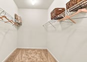 Thumbnail 13 of 34 - A walk in closet with a carpeted floor and clothes hanging on racks.