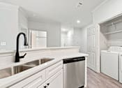 Thumbnail 5 of 34 - A white kitchen with a black faucet and a black trash bin.