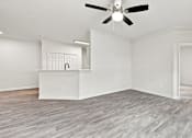 Thumbnail 3 of 34 - A room with a ceiling fan and light fixture, a white cabinet with a black handle, and a wooden floor.